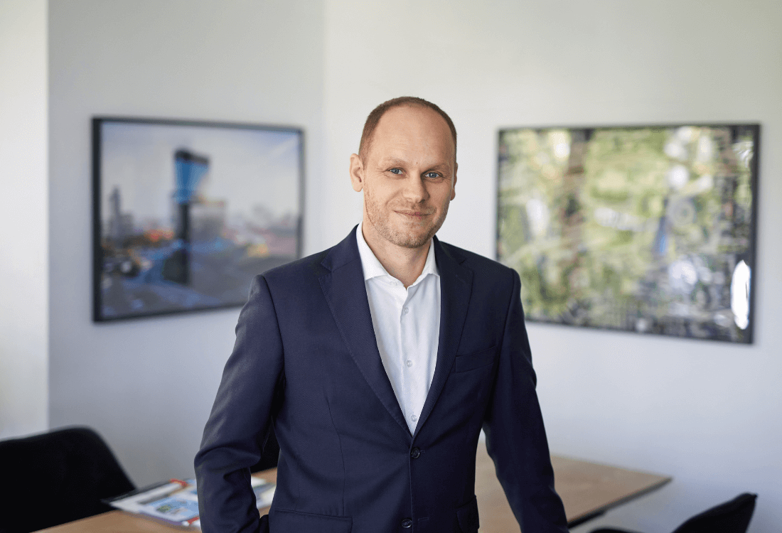 Na pierwszym planie wiceprezes Projekt Solartechnik Krzysztof Czajka uśmiechnięty oparty o biurko w swoim gabinecie w siedzibie w Katowicach