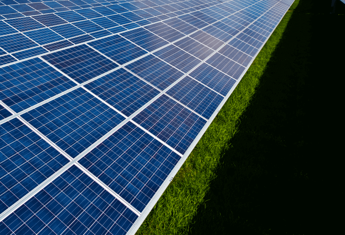 Wielkopowierzchniowa farma fotowoltaiczna wybudowana przez Projekt Solartechnik. Z lewej strony rzędy niebieskich paneli z prawej pas zacienionej zielonej trawy